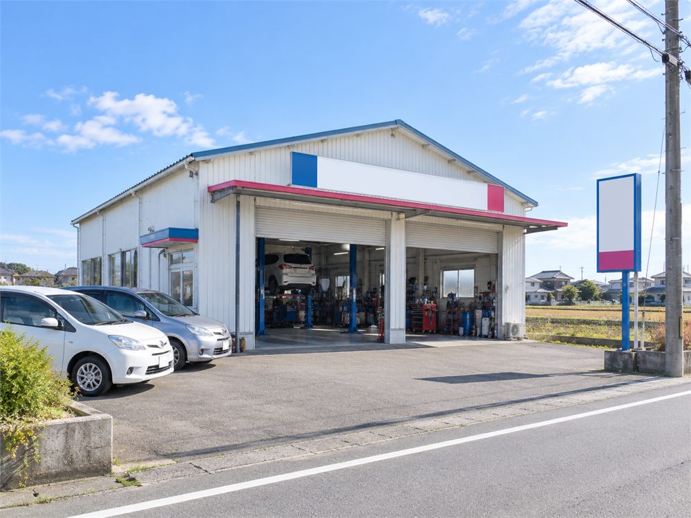 シャッターが並ぶ平屋建ての整備工場の外観と前庭